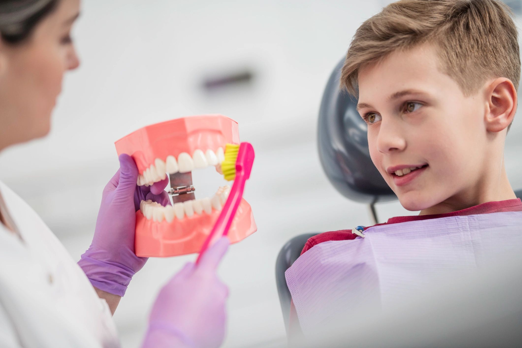 Dental hygienist smiling while helping a child learn brushing