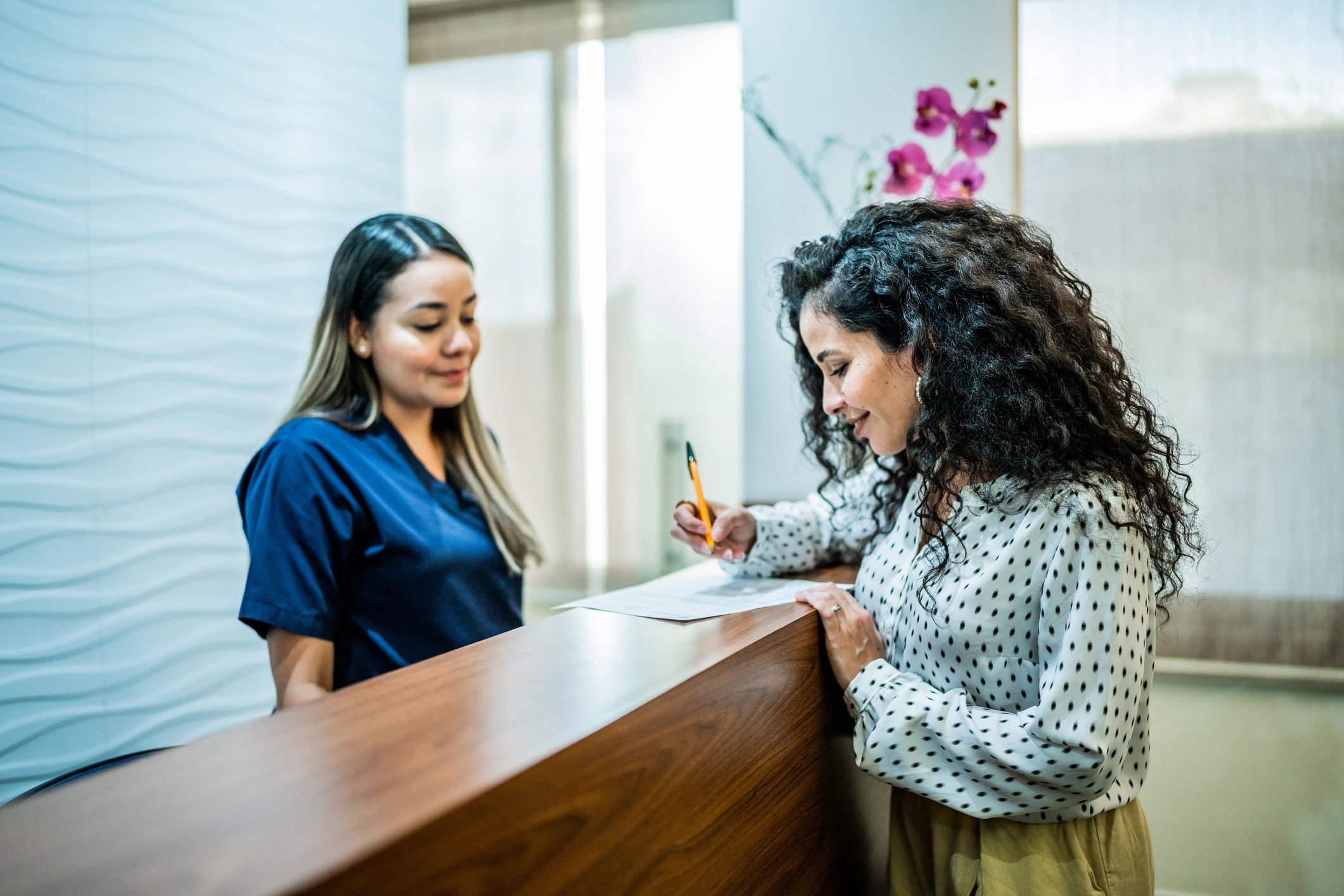 Patient speaking with the front desk team at a dental office reception