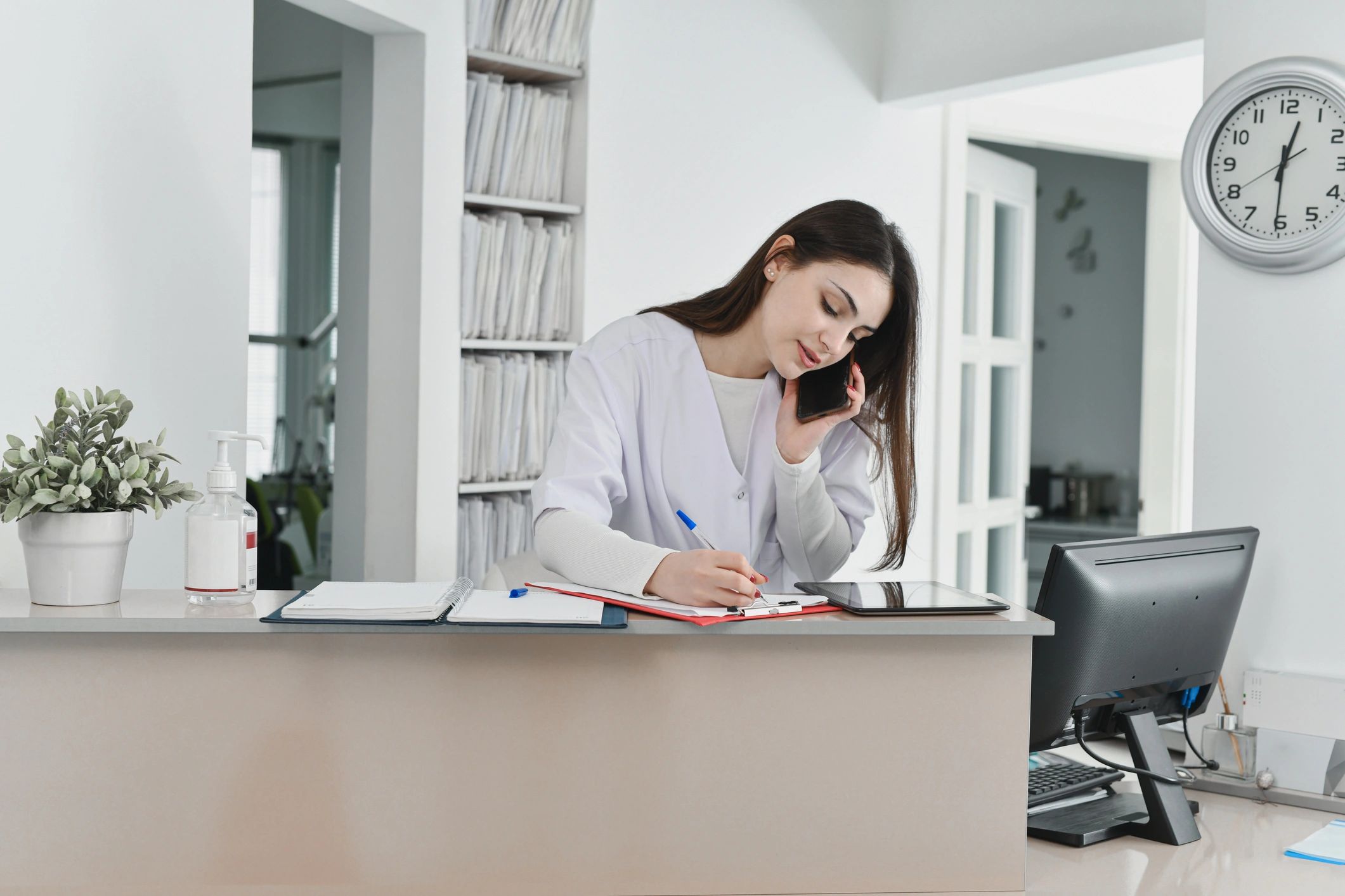 Dental receptionist writing appointment details on a clipboard