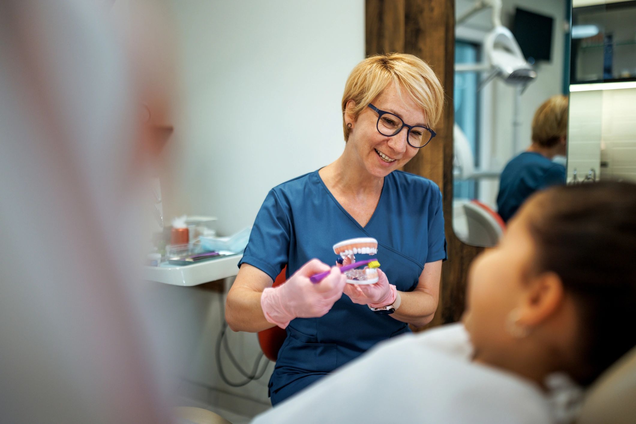 Dentist teaching a child proper brushing with a dental model